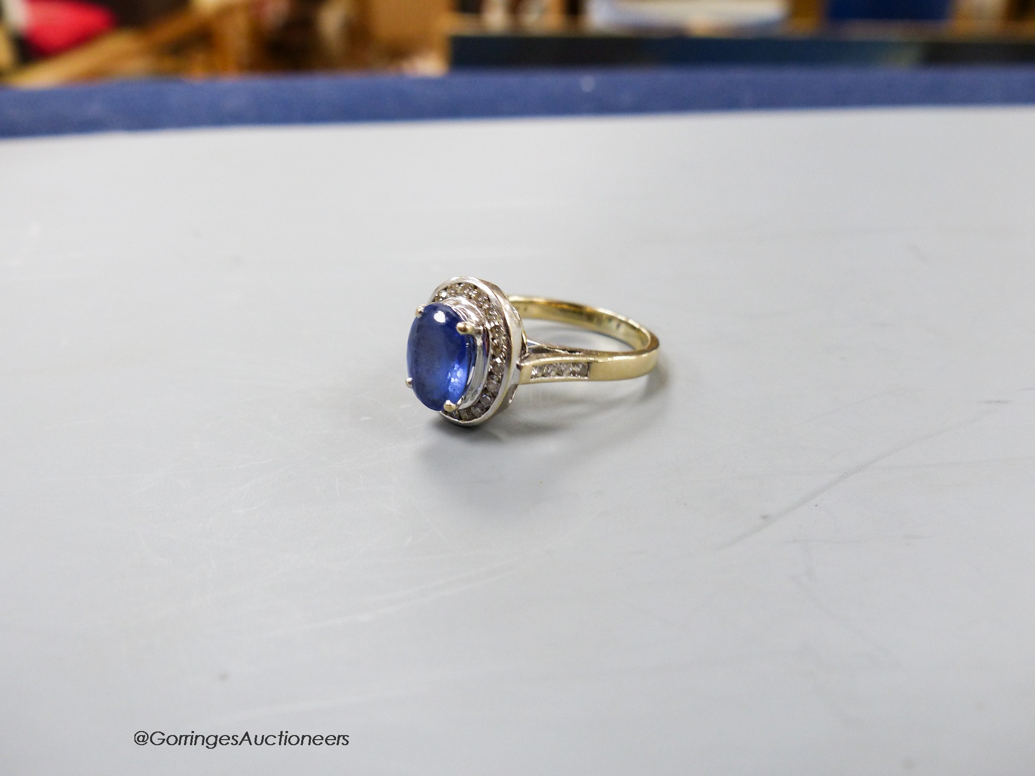 A modern 750 yellow metal, tanzanite and diamond chip oval cluster ring, size P, gross weight 9 grams